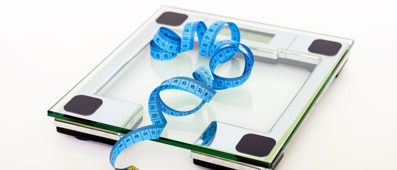 Digital glass weighing scale with a blue measuring tape