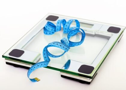 Digital glass weighing scale with a blue measuring tape